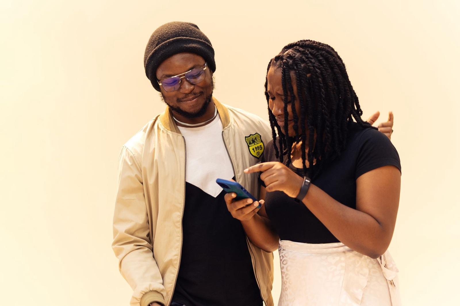 Two people in Lagos smiling as they look at a phone together.